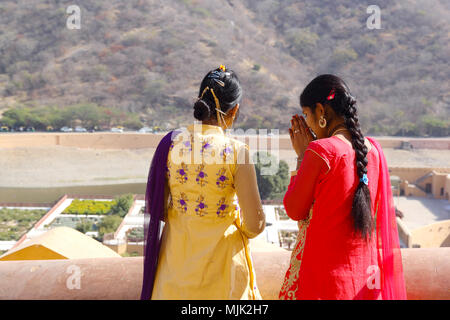 Deux inconnus les filles indiennes priant sur les murs de Fort Amber à Jaipur, Inde. Banque D'Images