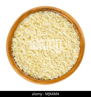 Flocons de millet dans bol en bois. La lumière jaune, millet laminées, utilisé pour les bouillies, de muesli et de la cuisson. Sans gluten de blé et de céréales. Macro photo isolées. Banque D'Images