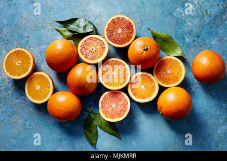 Orange sanguine entières ou coupées en tranches sur une surface bleue (vu du dessus). Banque D'Images