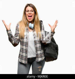 Jeune étudiante Femme avec sac à dos et casque heureux et surpris de l'expression d'encouragement geste wow Banque D'Images