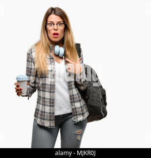 Jeune étudiante Femme avec sac à dos et casque heureux et surpris cheering exprimant wow geste, pointant avec le doigt Banque D'Images