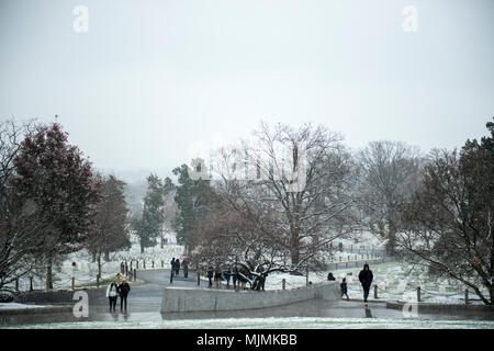 Le cimetière national d'Arlington est un cimetière militaire américain situé à Arlington, en Virginie, administré par le département de l'armée. Les visiteurs se promènent le long du terrain lors des premières chutes de neige de la saison le 9 décembre 2017. L'image d'archive documente la météo hivernale à travers le paysage du cimetière et les tombes marquées. Banque D'Images