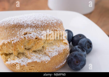 Scone traditionnel britannique sur une plaque blanche, cinq des bleuets sur le côté droit, en l'heure du thé Banque D'Images