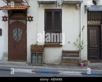 Fragment de la rue dans le quartier juif de la vieille ville de Jaffa : murs blancs, portes et fenêtres en fer massif, pot avec plante sur le trottoir, d'Israël. Banque D'Images