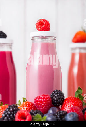 Bouteilles en verre avec des baies d'été sur fond de bois smoothie.Strwberries raspberies et avec les bleuets et les mûres. Banque D'Images