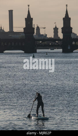 04 mai 2018, l'Allemagne, Berlin : un stand up paddler se déplace vers l'Oberbaumbruecke au coucher du soleil. Photo : Paul Zinken/dpa Banque D'Images