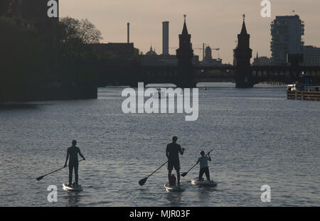 04 mai 2018, l'Allemagne, Berlin : un groupe de stand up paddlers aller vers l'Oberbaumbruecke au coucher du soleil. Photo : Paul Zinken/dpa Banque D'Images