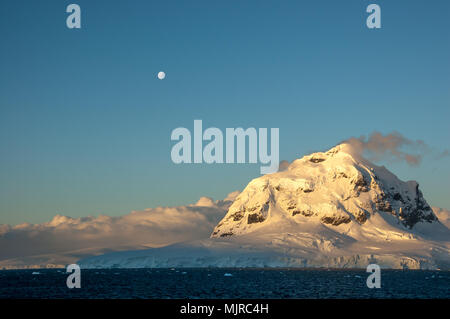 Dans l'été antarctique, le soleil près de horizon et peint en blanc neige tons délicats de orange, jaune et rose. Banque D'Images