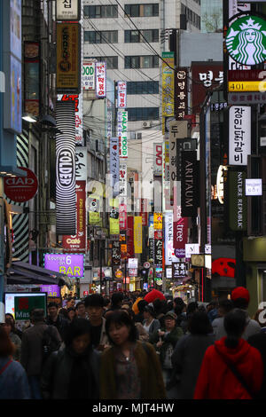 Les gens affluent à l'animation de la zone Myeongdong de Séoul, Corée du Sud, dans la soirée pour faire des achats, de l'alimentation de rue de l'échantillon, vérifier les modes, les tendances. La foule dense. Banque D'Images