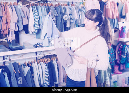 Femme enceinte choisit des vêtements pour l'avenir d'un membre de la famille dans le magasin Banque D'Images