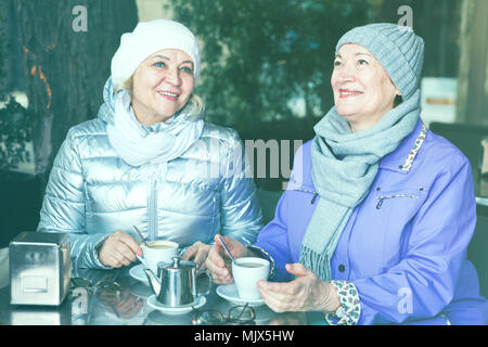 Les femmes âgées souriant appréciant de temps ensemble à l'extérieur confortable cafe à jour d'automne Banque D'Images