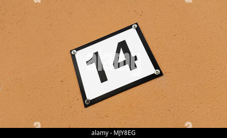 Un numéro de maison signer avec le numéro quatorze isolé sur un mur de couleur brune. Banque D'Images