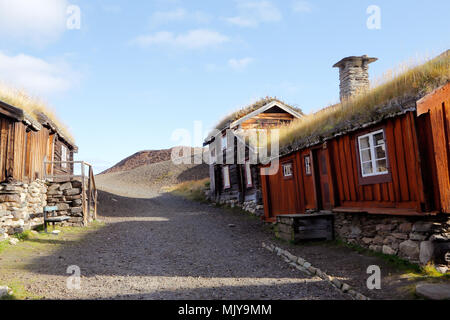 Vieux bâtiments en bois avec des toits de chaume à côté du terril dans la ville minière de Røros en Norvège. Banque D'Images