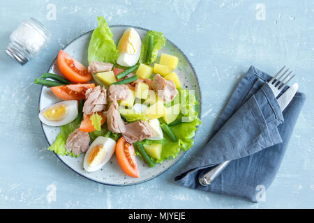 Salade niçoise au thon, oeufs, pommes de terre, haricots verts et tomates. Salade niçoise traditionnelle bleu sur fond de bois, vue du dessus, copiez l'espace. Banque D'Images
