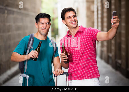 Deux hommes sont à pied avec de la bière et de faire près de selfies attractions touristiques à Barcelone. L'accent sur l'homme droit Banque D'Images