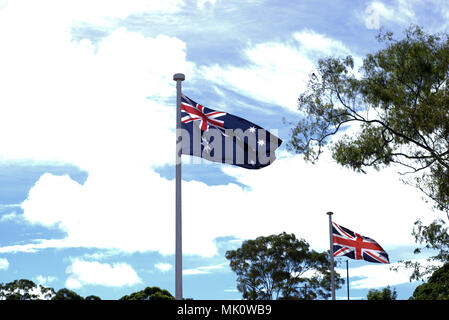 Battant pavillon australien et britannique, le drapeau en arrière-plan sur l'ANZAC day. Brandissant des drapeaux de l'Australie et l'Angleterre avec ciel bleu et nuages blancs. Banque D'Images