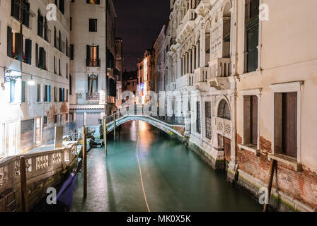 Vue de nuit sur un canal typique de Venise avec le sentier de la lumière d'un bateau Banque D'Images