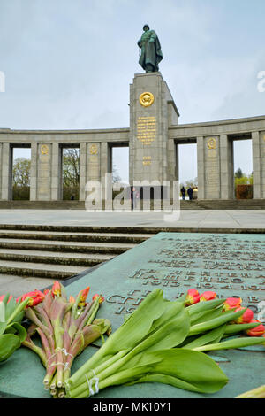 Berlin, Allemagne - 14 Avril 2018 : Tulipes sur la pierre tombale gravée avec les noms des héros de l'Union soviétique en face de statue en bronze d'un soldat soviétique Banque D'Images