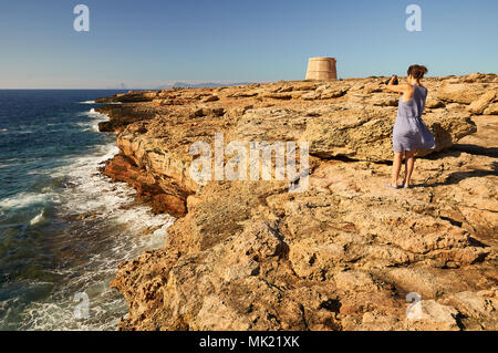 Femme photographiant la côte près de la tour de défense avec Sa Gavina Es Vedrá Island dans la distance à Formentera (Baléares, Espagne) Banque D'Images