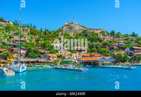 KALEKOY, TURQUIE - 5 mai 2017 : Château Simena Byzantine surmonté le rocher du village avec de belles maisons, jardins, cafés touristiques vert et en retrait Banque D'Images