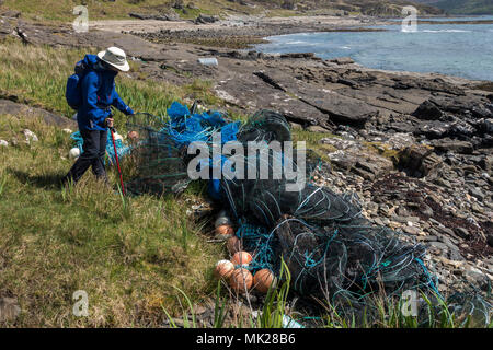 Walker examinant les plastiques et les engins de pêche en nylon sur la plage écossais, Isle of Skye, Scotland, UK Banque D'Images