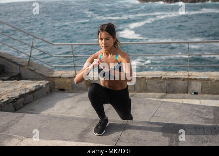 Young attractive woman à l'accent tout en exerçant sur les escaliers par la mer