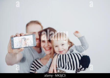 Famille, vacances, la technologie et les gens - smiling mother, father and little girl making avec caméra selfies sur fond blanc Banque D'Images