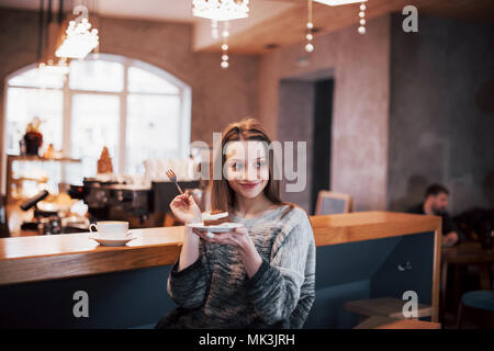 Happy smiling young woman using phone dans un café. Belle fille de couleurs tendance printemps Banque D'Images