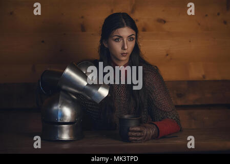 Portrait de belle fille médiévale warrior dans une maille le capot avec le casque dans les mains Banque D'Images