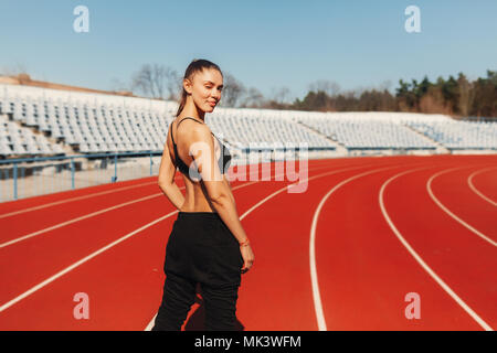 Bien paraître et se sentir bien. Vu de dos femme saine jogger dans le sport vêtements de style sur le stade dans la matinée. Prêt à fonctionner Banque D'Images