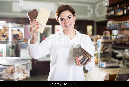 Smiling girl décider sur la meilleure barre de chocolat en pâtisserie Banque D'Images