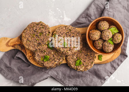 Vegan burgers (haricots) et les boulettes de veau au persil sur une planche en bois, copie de l'espace. La nourriture végétalienne saine concept. Banque D'Images