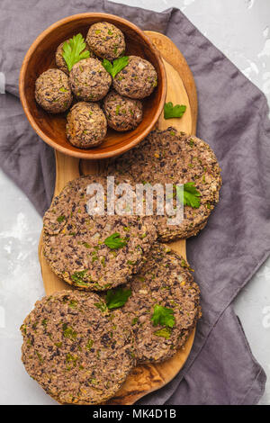 Vegan burgers (haricots) et les boulettes de veau au persil sur une planche en bois, copie de l'espace. La nourriture végétalienne saine concept. Banque D'Images