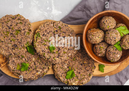 Vegan burgers (haricots) et les boulettes de veau au persil sur une planche en bois, copie de l'espace. La nourriture végétalienne saine concept. Banque D'Images