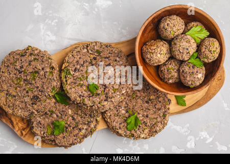 Vegan burgers (haricots) et les boulettes de veau au persil sur une planche en bois, copie de l'espace. La nourriture végétalienne saine concept. Banque D'Images