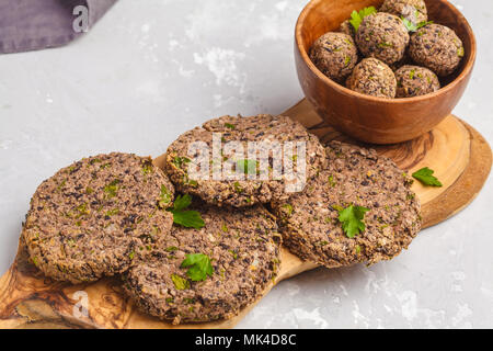 Vegan burgers (haricots) et les boulettes de veau au persil sur une planche en bois, copie de l'espace. La nourriture végétalienne saine concept. Banque D'Images