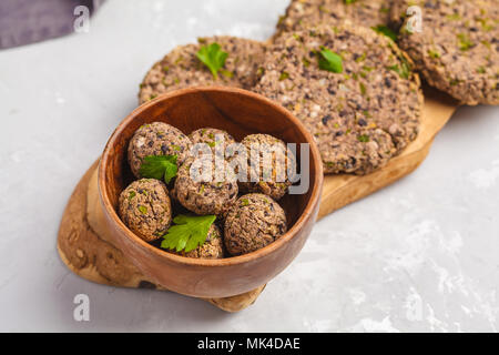 Vegan burgers (haricots) et les boulettes de veau au persil sur une planche en bois, copie de l'espace. La nourriture végétalienne saine concept. Banque D'Images