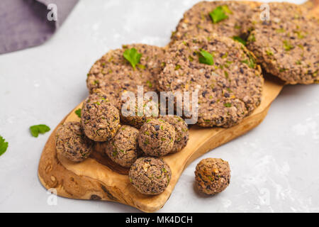 Vegan burgers (haricots) et les boulettes de veau au persil sur une planche en bois, copie de l'espace. La nourriture végétalienne saine concept. Banque D'Images