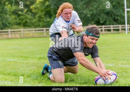 Touch rugby amateur - tournoi player marquant un essai comme un défenseur tend la main pour s'attaquer à lui Banque D'Images