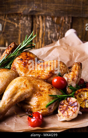 Poulet rôti en papillon avec le citron, les tomates et les herbes de romarin sur table en bois rustique, délicieux dîner de Thanksgiving ou le dimanche Banque D'Images