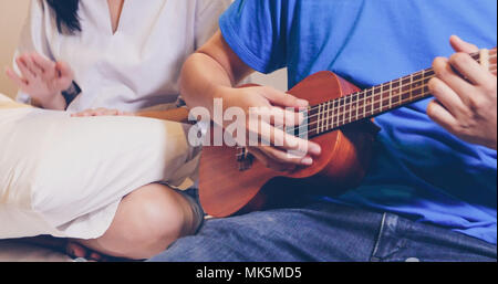 Amour couple playing Ukulele et de la guitare au lit Banque D'Images