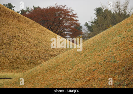 Une vue à travers deux immenses anciens tumulus funéraires du royaume de Silla en Tumuli Park à Gyeongju, Corée du Sud, sur l'image. 24 mounds sont ici. Banque D'Images