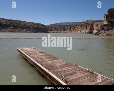 Les parois du canyon coloré de Bighorn Canyon National Recreation Area avec dock en bois en premier plan avec ciel bleu au-dessus. La rivière Bighorn boueux est vu. Banque D'Images