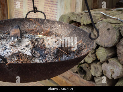 Gravure de cendres dans la cuisinière avec le mur de briques et de bois de chauffage sur fond de bois Banque D'Images