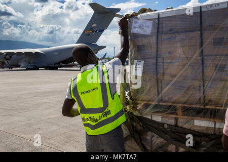 Un groupe de travail pour la Mission de la Fondation Haïtienne de l'Espoir (Mission d'Espoir) supprime la sangle de transport une palette d'aliments secs colis livrés par un U.S. Air Force C-17 Globemaster III à l'aéroport international Toussaint Louverture, Port-au-Prince, République d'Haïti, le 18 novembre 2017. Le 732e Escadron de transport aérien, qui est affecté à la 514e Escadre de mobilité aérienne livré 76 410 livres de nourriture composée de paquets de riz enrichi de protéines de soja et l'orge en herbe en poudre de jus et mélanger pour Haïti. La livraison a été possible parce que le programme permet aux donateurs de Denton disponible à l'utilisation de l'espace sur cargo militaire américain Banque D'Images