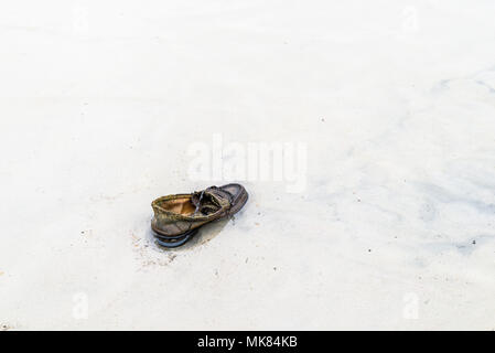 Utilisé et abandonné sans lacets de chaussures ou en eau très peu profonde sur une plage de sable. Banque D'Images