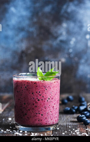 Frappé aux bleuets décoré de feuilles de basilic. Verre de bleuets sains ou berry smoothie sur tableau noir, selective focus. Végétarien ou Végétalien nutriti Banque D'Images