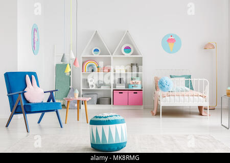 Pouf fauteuil bleu à motifs colorés dans près de chambre d'enfant intérieur avec une affiche au-dessus de lit blanc Banque D'Images