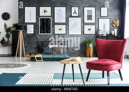 Close-up de fauteuil rouge à côté d'une table en bois avec livre sur tapis bleu à l'intérieur chambre à coucher confortable Banque D'Images