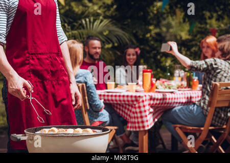 Close-up of man grilling food durant une fête d'anniversaire dans l'été Banque D'Images